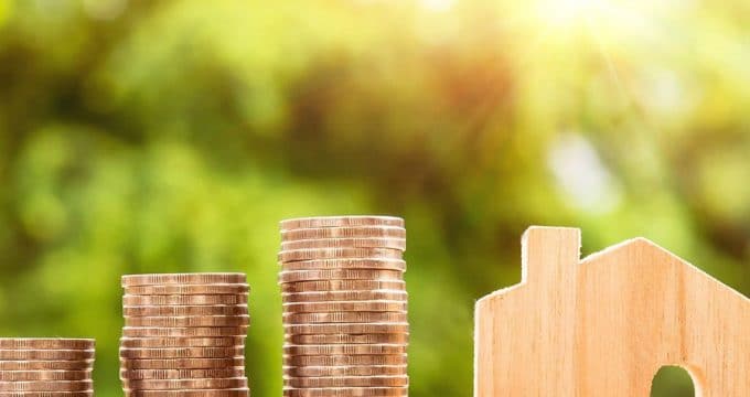 Maéison en bois et pile de pièces de monnaie