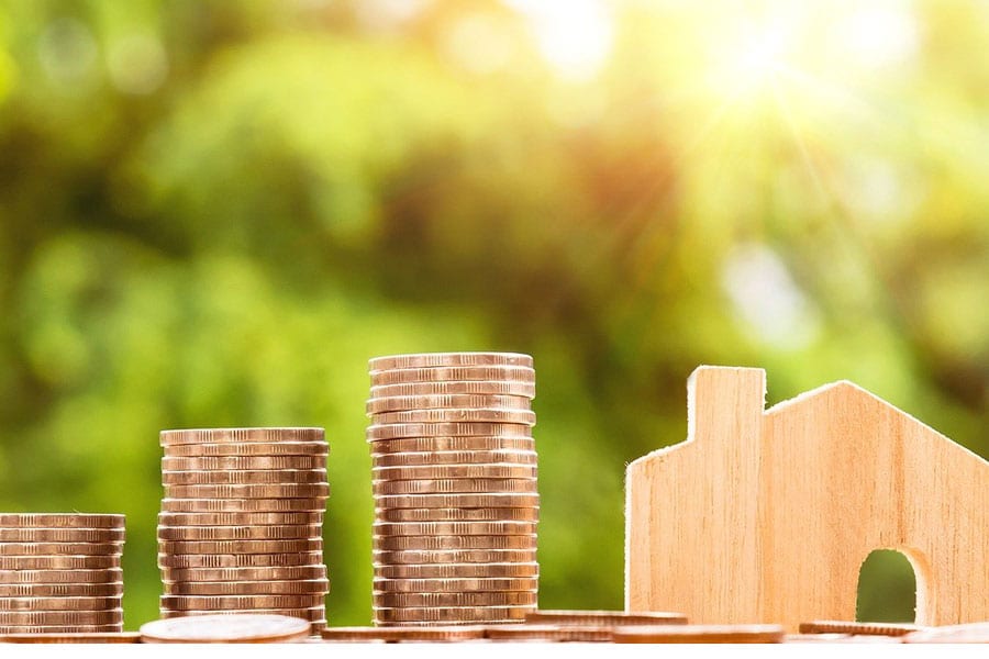 Maéison en bois et pile de pièces de monnaie