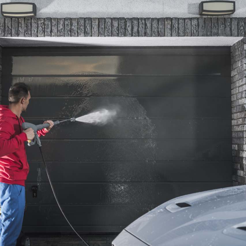 homme nettoyant porte de garage au nettoyeur haute pression.