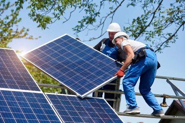 deux jeunes techniciens montent de lourds panneaux solaires 1