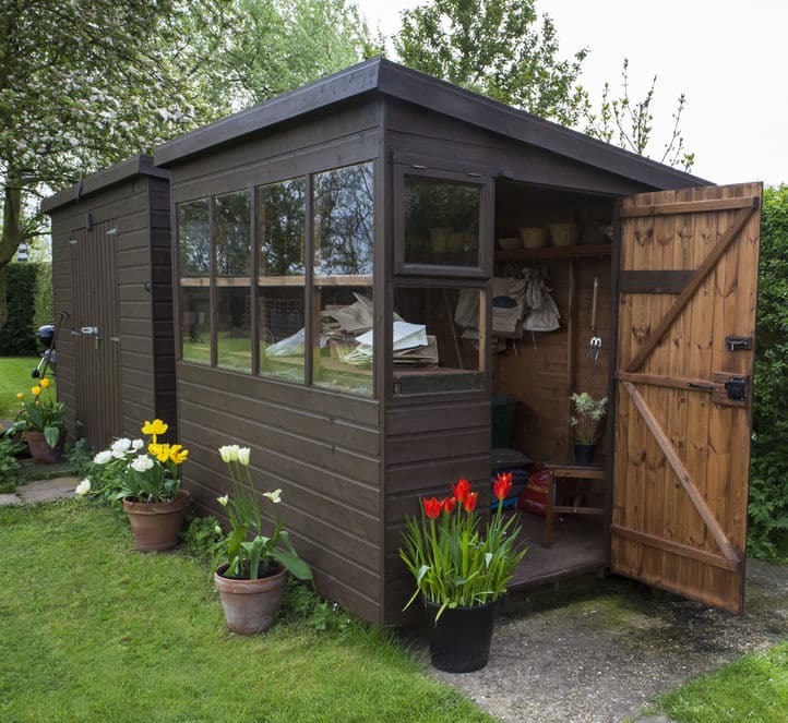 garden shed exterior with door open, tools, flowers, and plant p