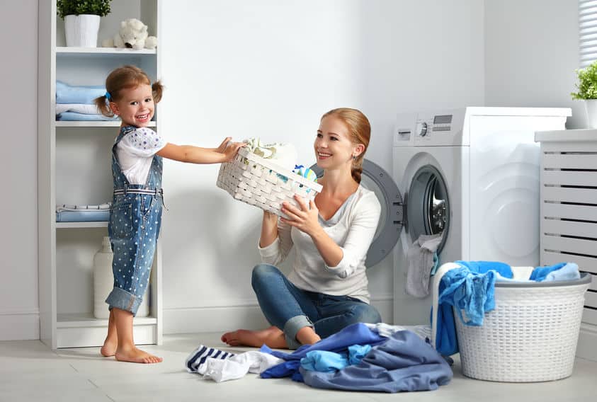 family mother and child little helper in laundry room near washing machine